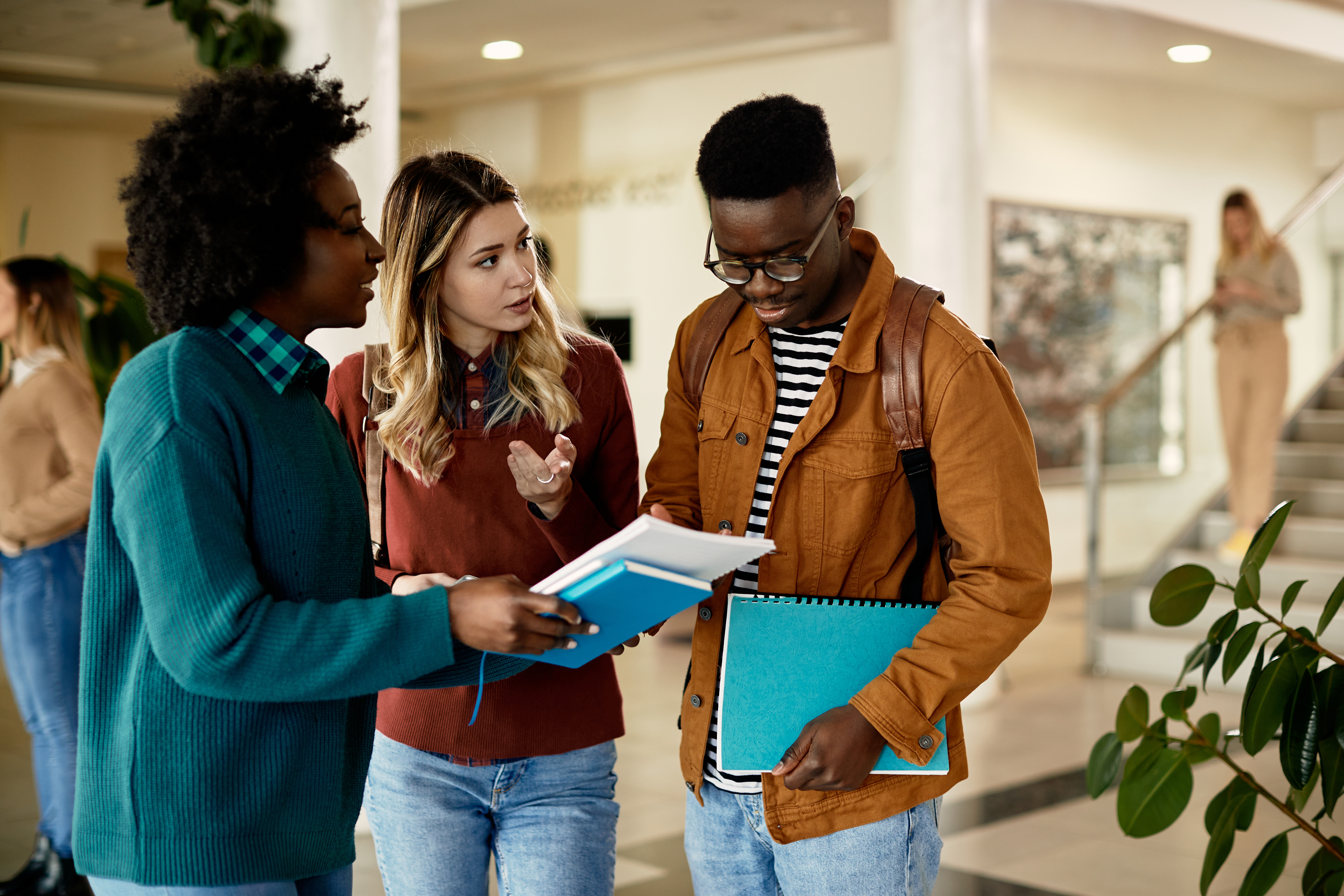 Group of college friends talk while going through lecture in hallway.